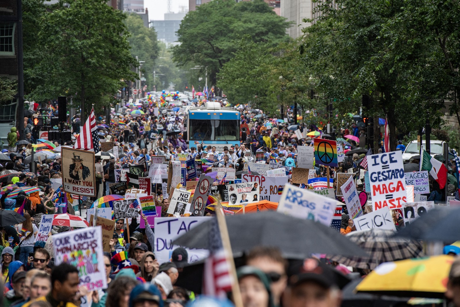 Protesters carrying anti-Trump administration signs march down a street.