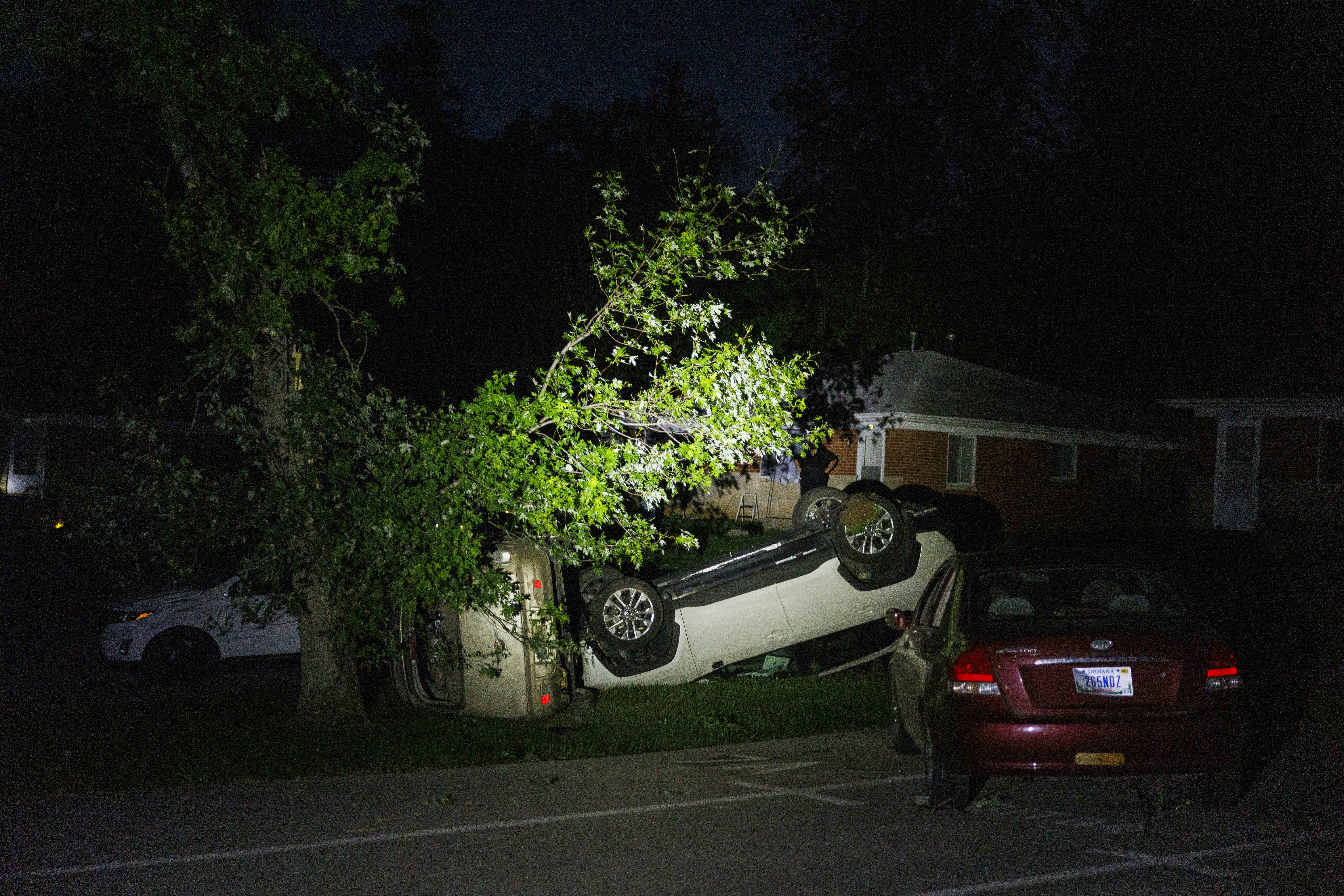 Several cars lie upside down or on their sides, flipped over by a tornado.