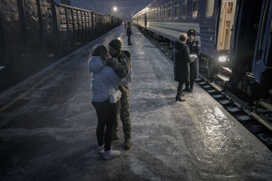 A soldier and his girlfriend say goodbye at a train station.