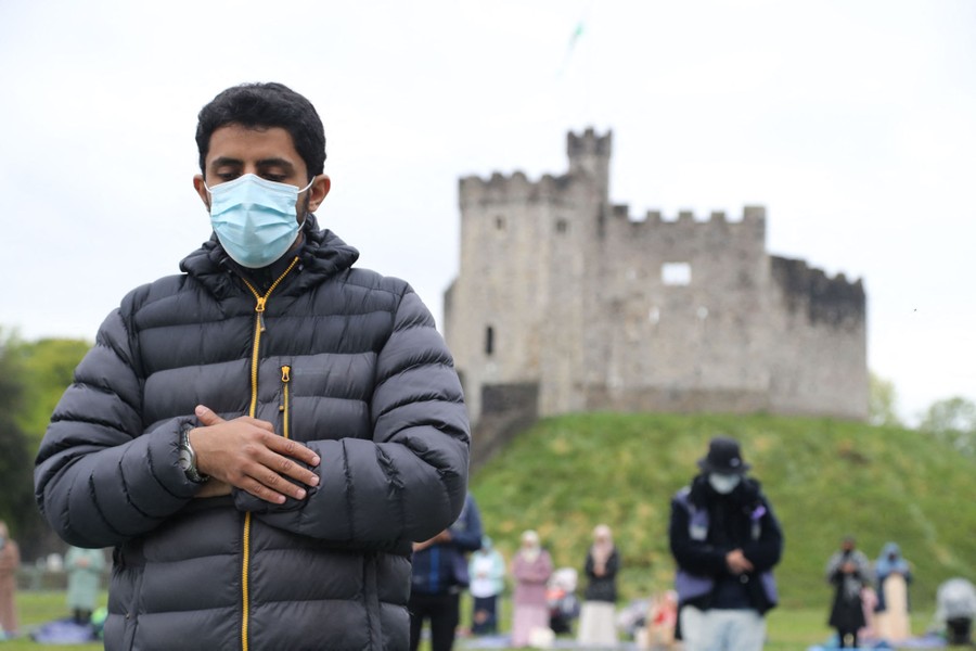 People gather near a castle to perform prayers together.