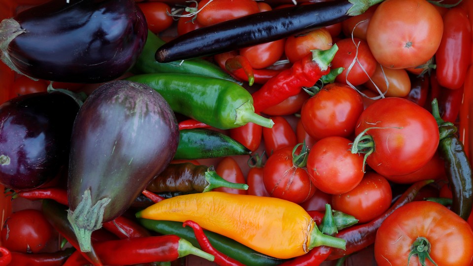 A basket of vegetables, including tomatoes, peppers, and eggplants.