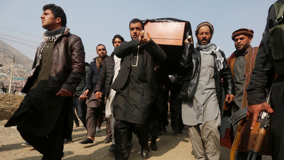 Afghan men carry a coffin.
