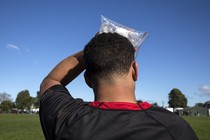 A soccer player holding a bag of ice to his head.