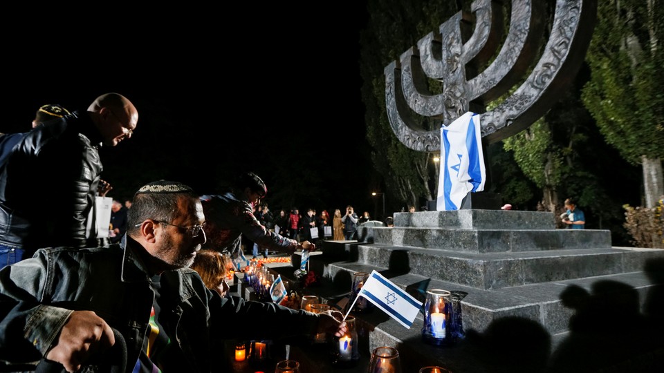 People place candles and Israeli flags during a ceremony commemorating the victims of Babi Yar on September 29, 2016.