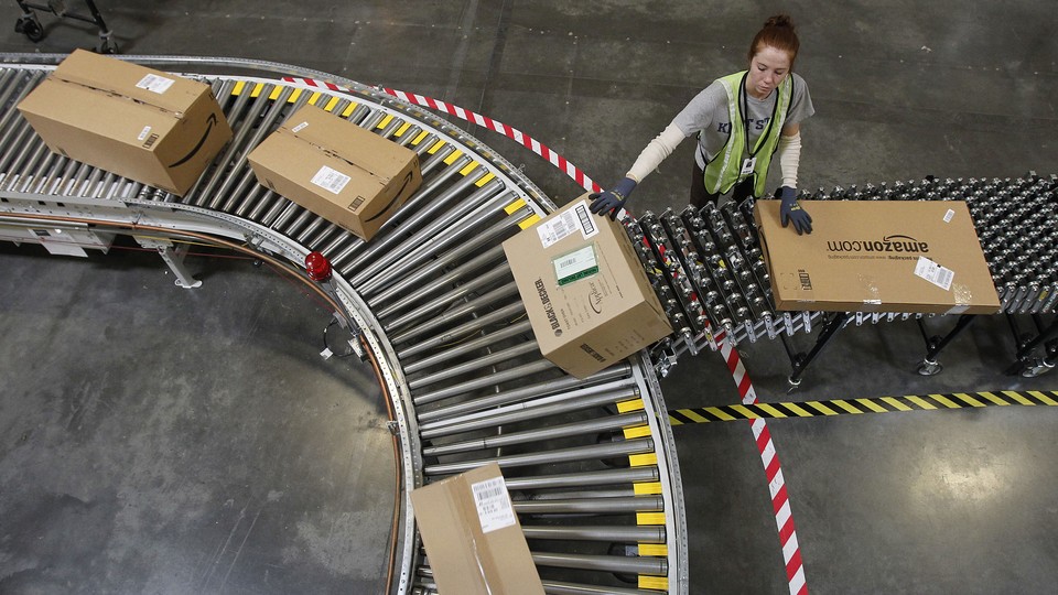 A worker loads Amazon packages onto a conveyor belt.