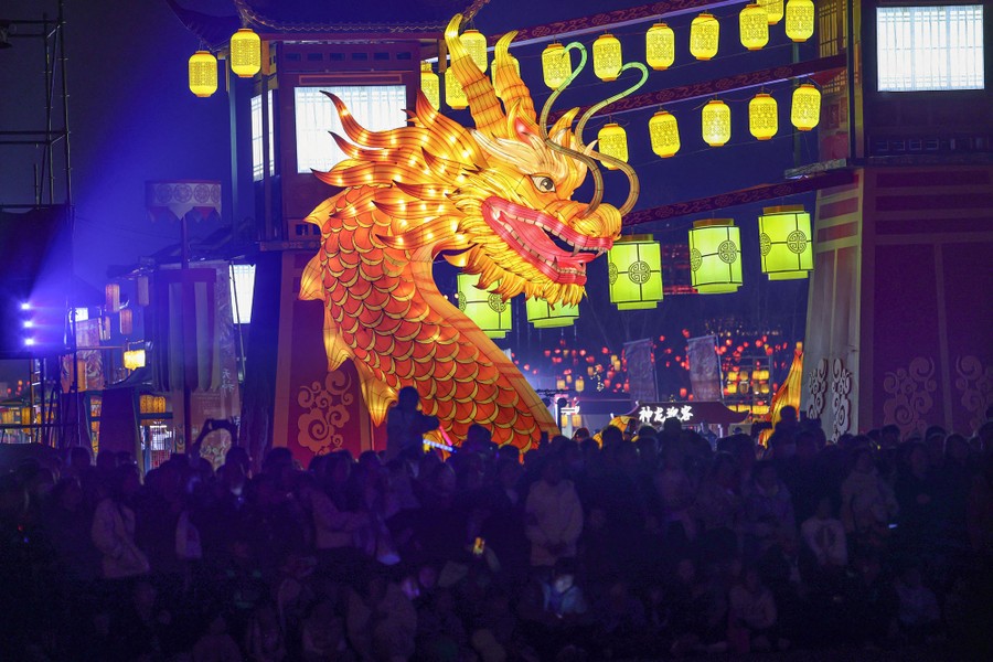 People crowd around a large, illuminated dragon sculpture.