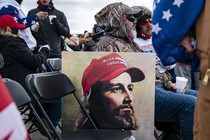 A painting of Jesus with a Make America Great Again hat leans against a chair