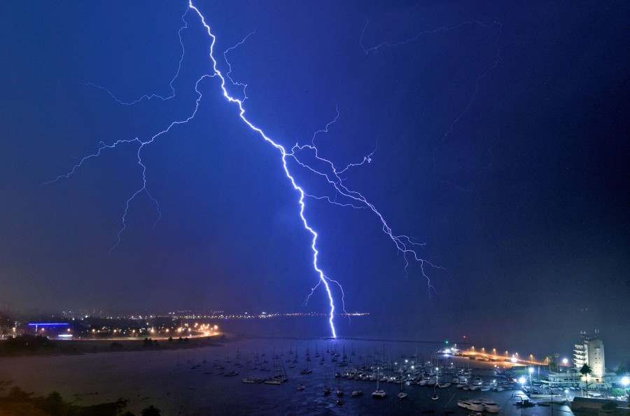 A lightning bolt strikes near a yacht club at night.