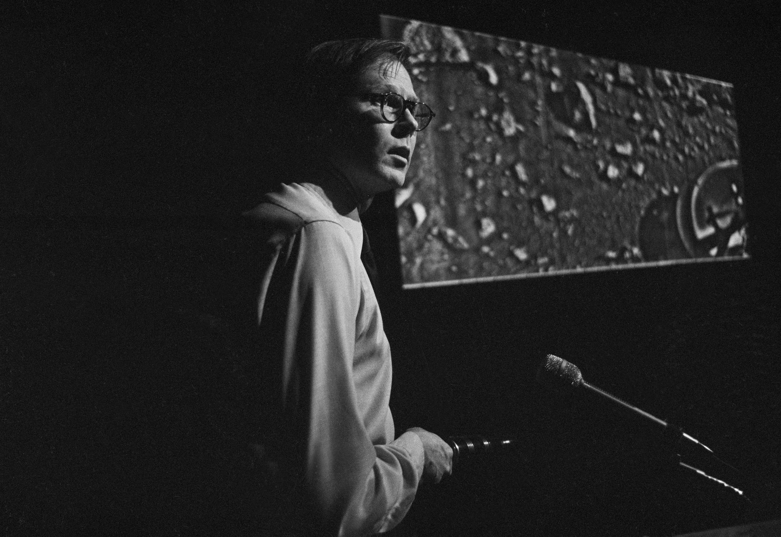 A man discusses a photo of the surface of Mars at a press conference.