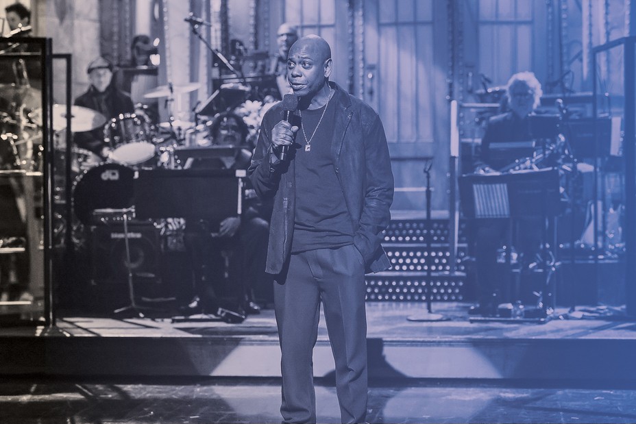 photo of Dave Chapelle with microphone opening SNL with band in background