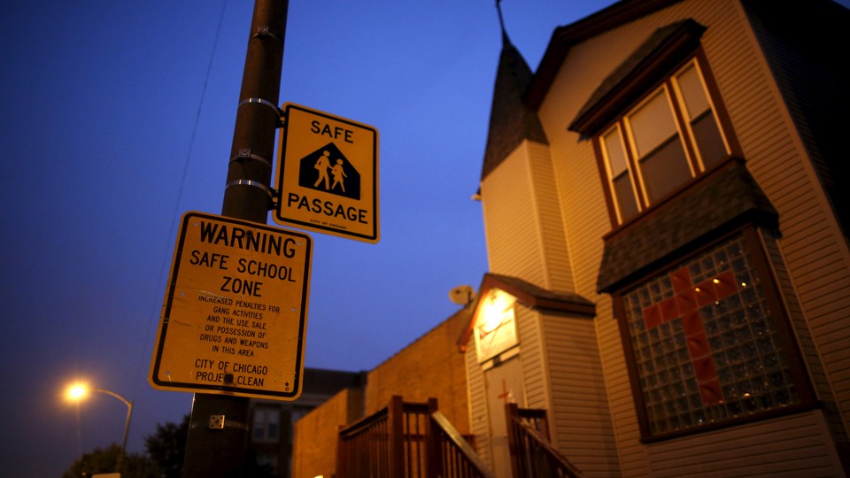 Taken at night, the photo shows a yellow safe-passage sign reading "Warning Safe School Zone" 