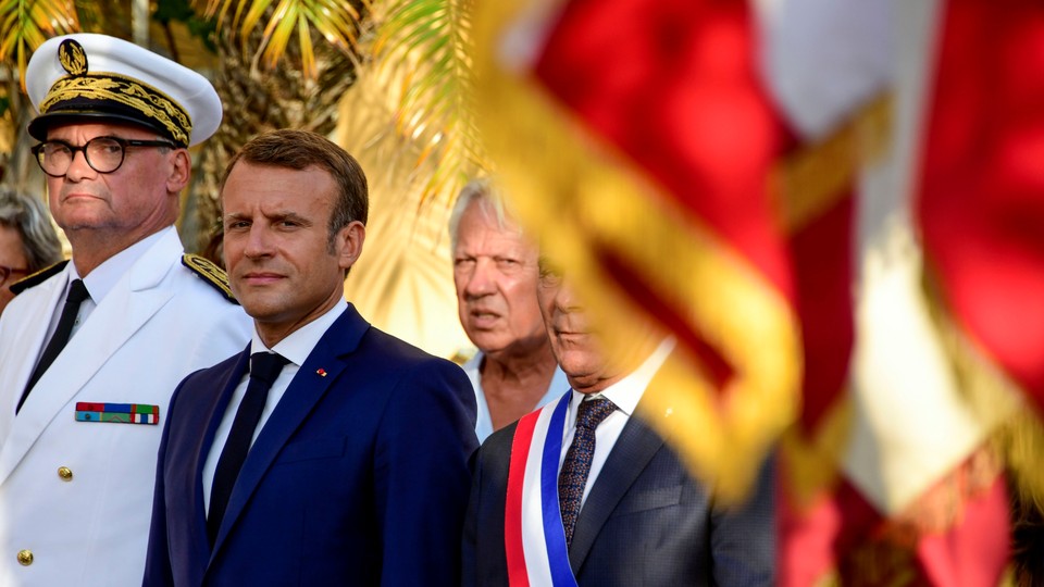 Emmanuel Macron stands at a ceremony alongside two other French officials.