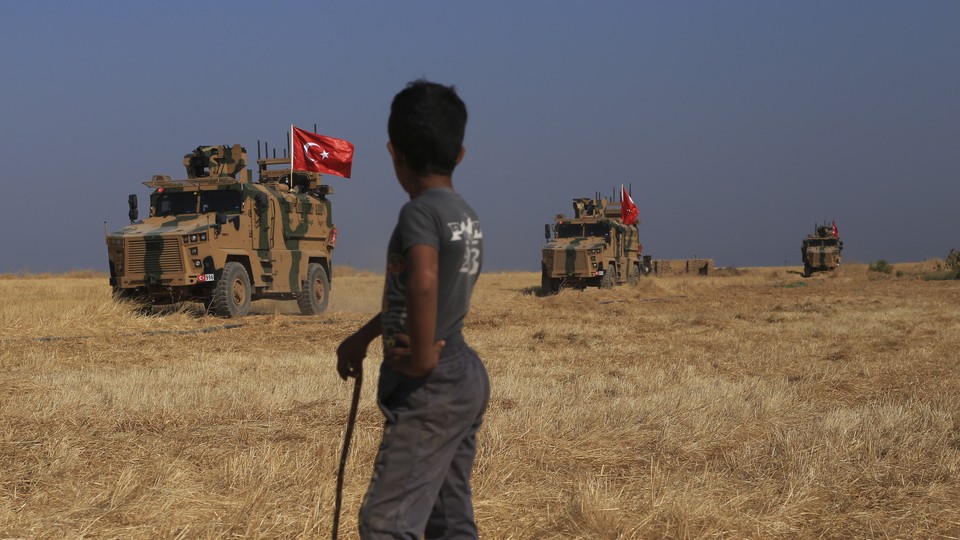 Turkish armored vehicles conduct a joint ground patrol with American forces in the "safe zone" on the Syrian side of the border with Turkey