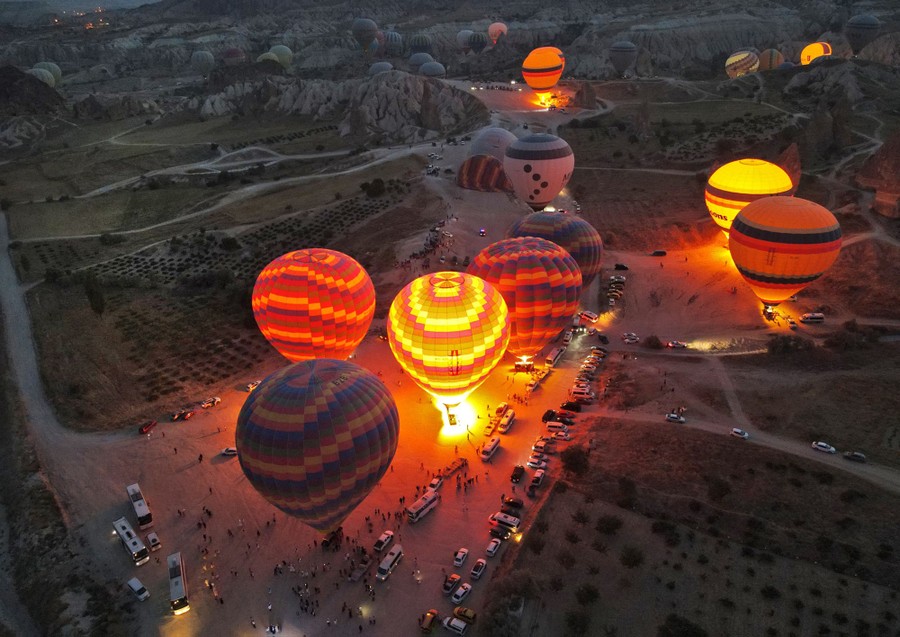 An aerial view of more than a dozen hot-air balloons preparing to launch