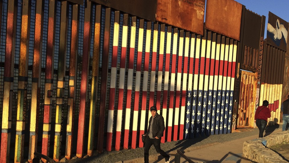 People walk past a mural painted on a border structure in Tijuana, Mexico.