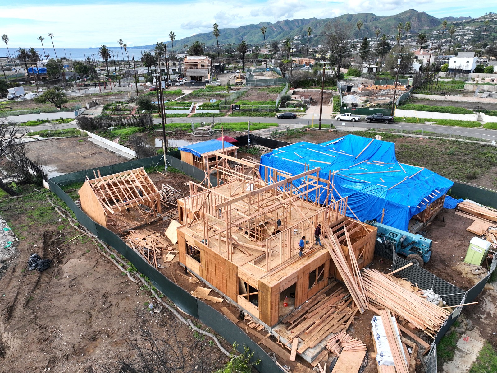 An aerial view of a home under construction, in a neighborhood of vacant lots and other newly-built homes.