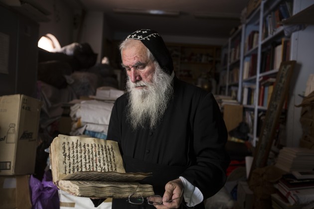 Shimon Can, the monk responsible for the library at St. Mark’s Syrian Orthodox Monastery, gazes at one of its manuscripts (Matilde Gattoni)