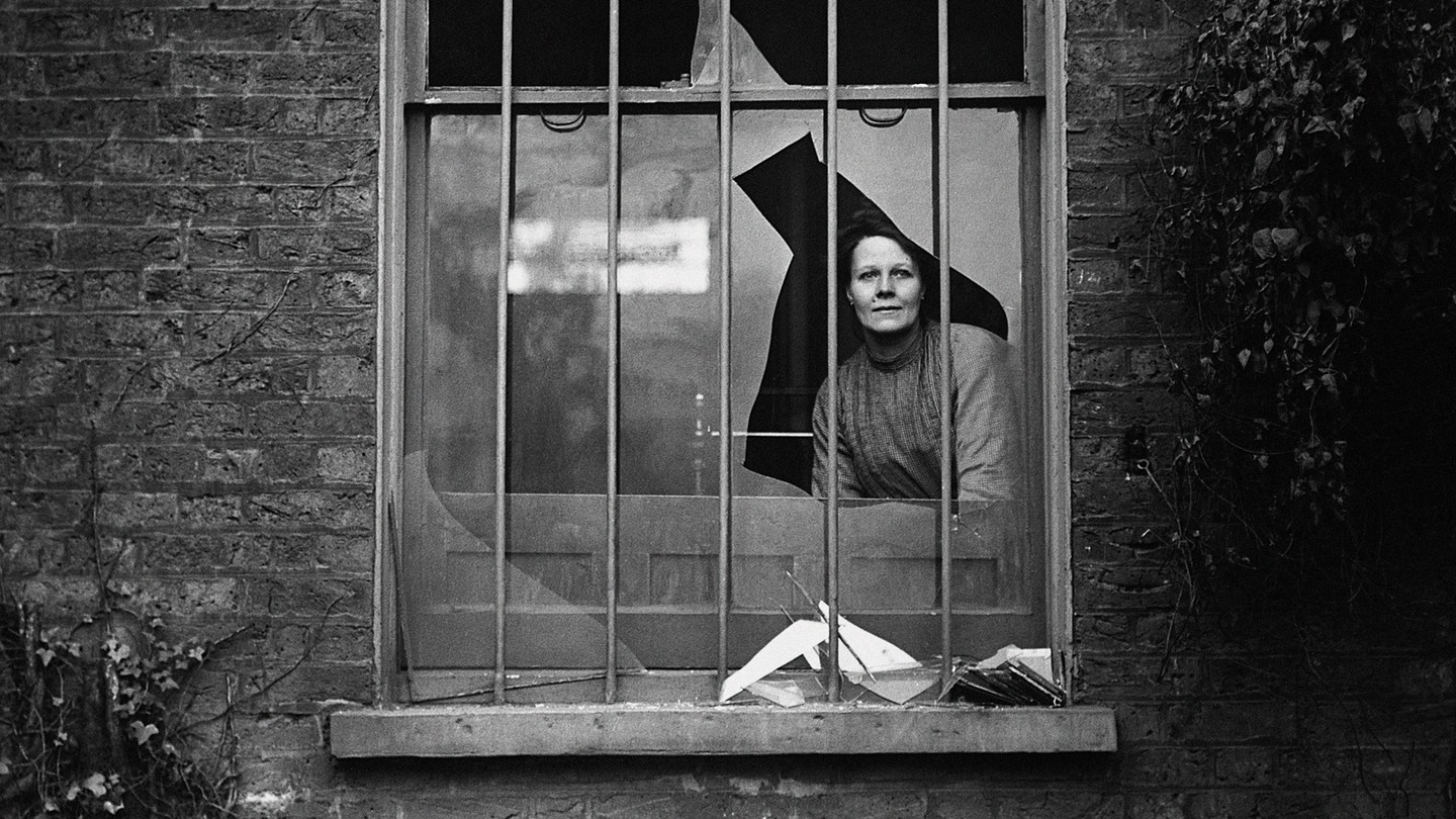 a photo of a woman staring out a broken window