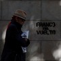 A woman walks past a graffiti which reads "Franco is back" in Barcelona, Spain on October 22, 2017. 