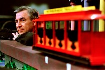 Fred Rogers resting near a trolley on a TV set