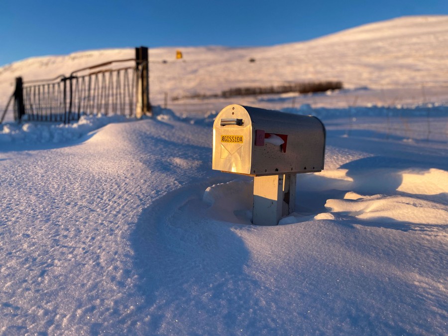 A mailbox stands in deep snow .