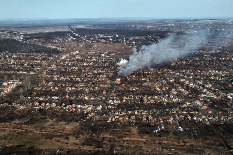 An aerial view of a residential area, with a house burning in the center of the image.