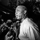 A black-and-white photo of Eric Adams being questioned by the press.