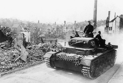 A German armored tank drives in front of a devastated city, one day before the surrender of France