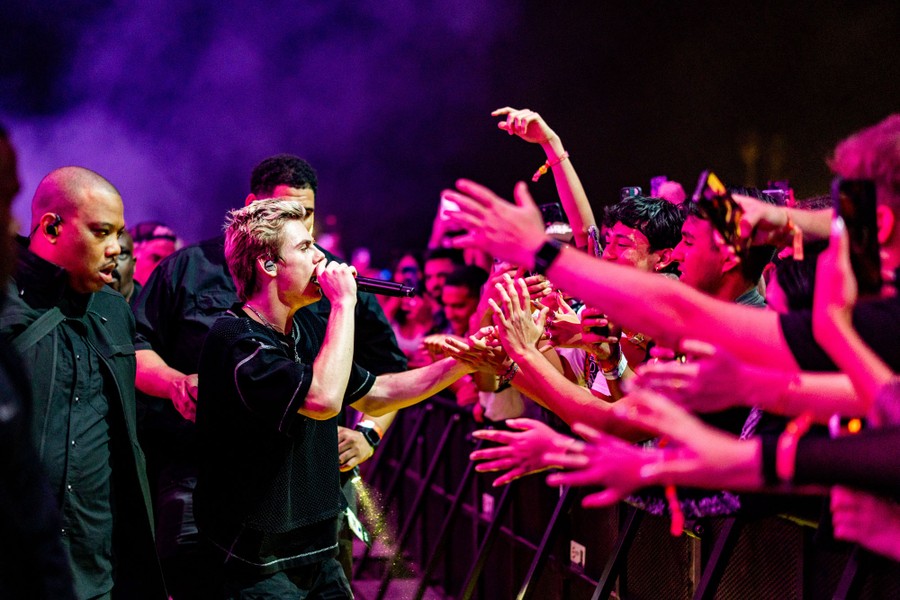 A performer sings into a microphone while giving high-fives to a large audience.