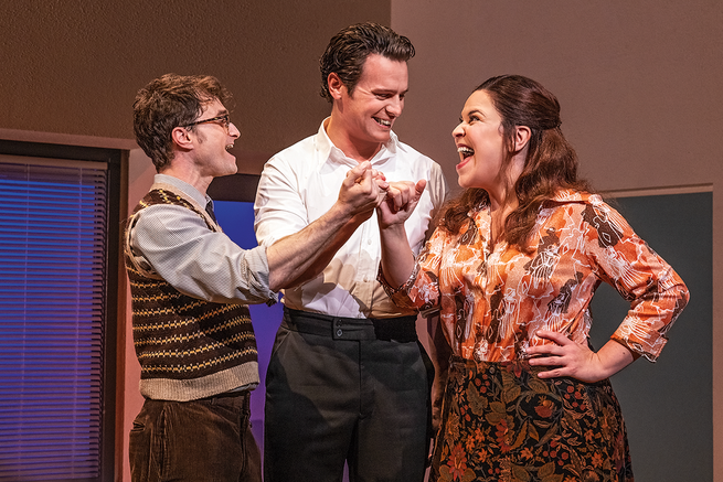 photo of Radcliffe, Groff, and Mendez smiling and joining hands during musical number