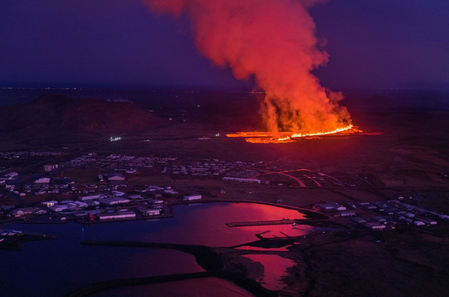 An aerial view of lava flowing toward a small town