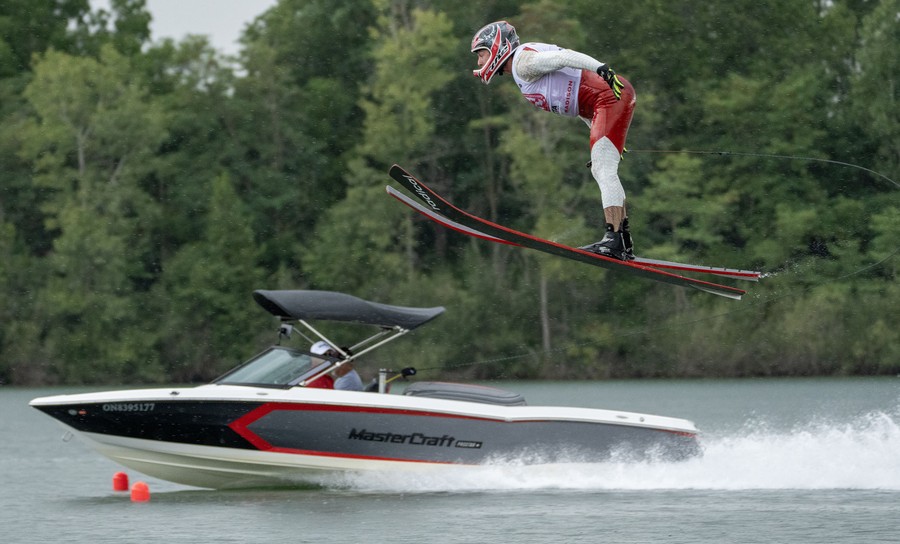 A waterskier in midair during a jump, with a speedboat in the background