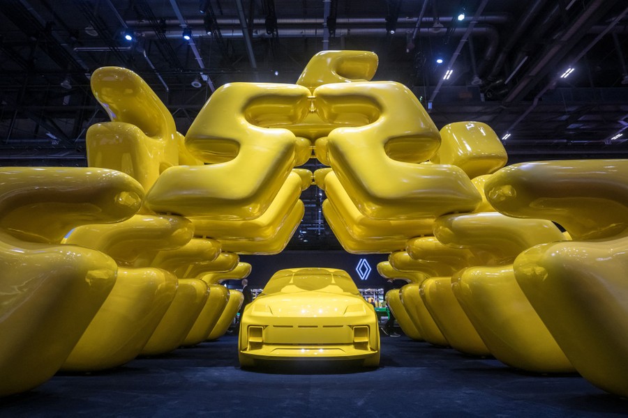 A mockup of a new car, completely yellow, sits beneath a large yellow stylized display.