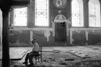 A man sits alone in a ruined synagogue in Russia.