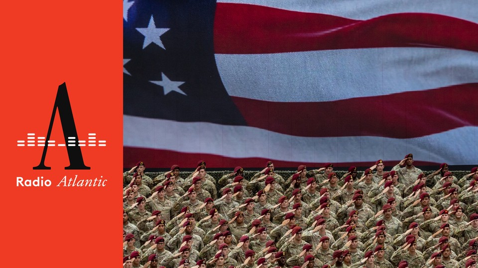 This photo shows a wide shot of U.S. army members saluting and wearing fatigues and matching red berets. Behind them is the image of the American flag