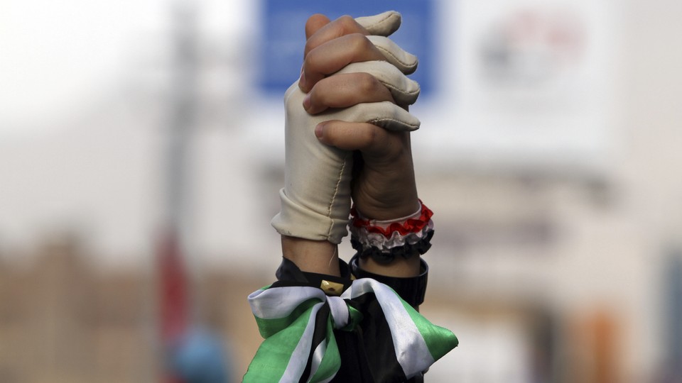 Women clasp hands during a pro-democracy march to demand Yemen's former President Ali Abdullah Saleh stand trial for the killings of protesters who demanded the end of his 33-year rule, in Sanaa on April 8, 2013. 