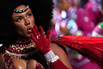 A person in a Carnival costume blows a kiss toward onlookers
