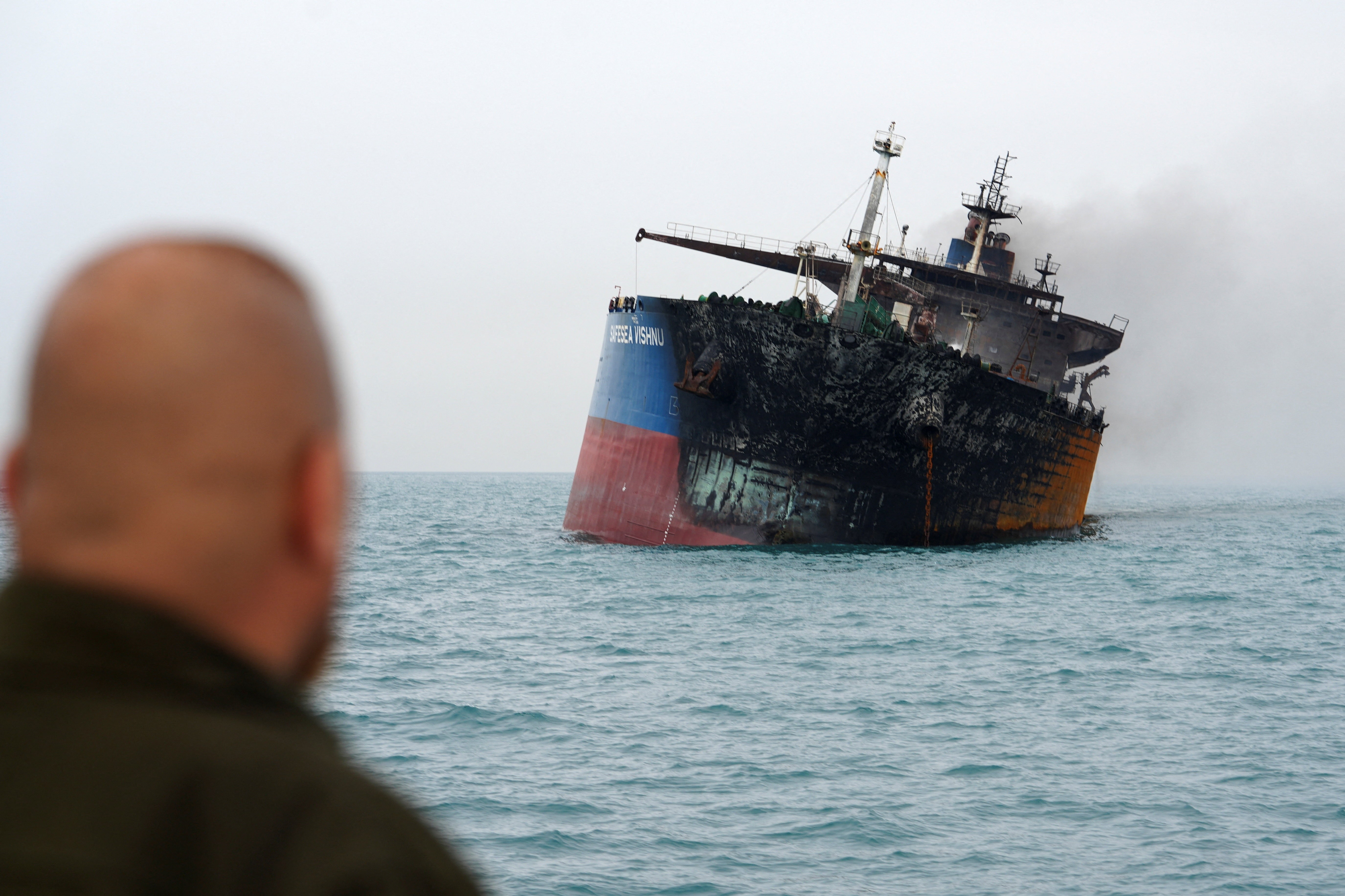 A scorched oil tanker lists, still smoking, at sea, after an attack.