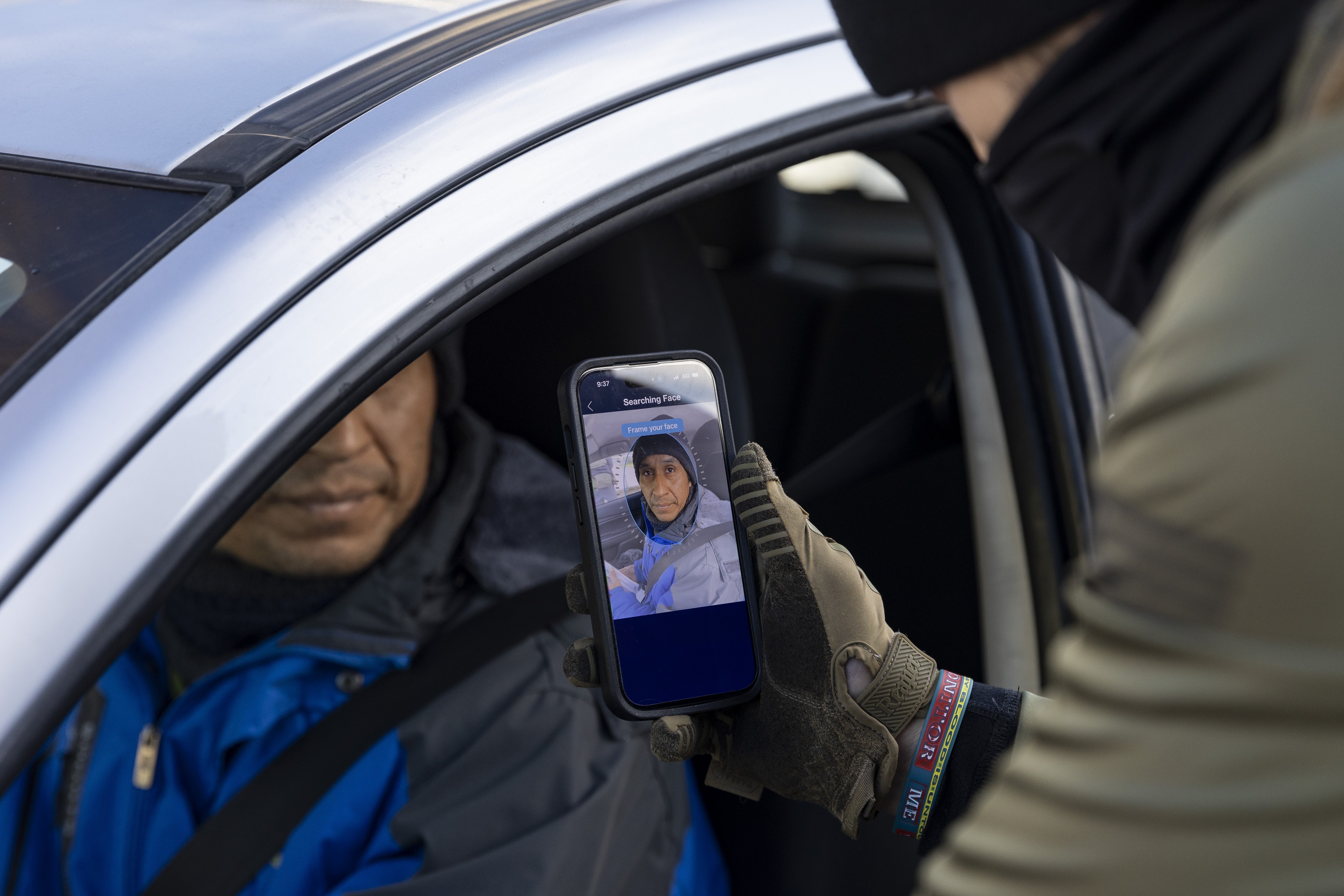 A Border Patrol agent scans the face of a driver using an app on their phone.