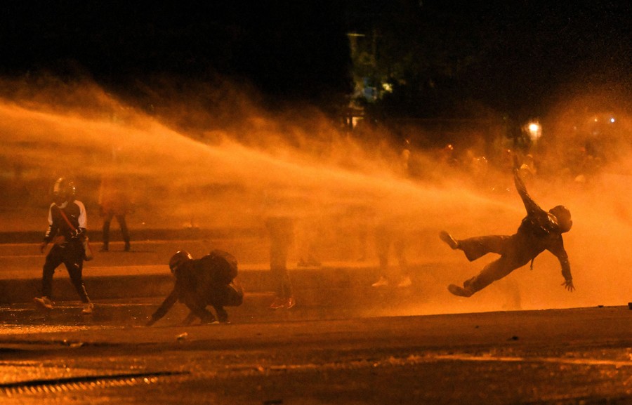 A protester is knocked off their feet by a powerful blast of water.