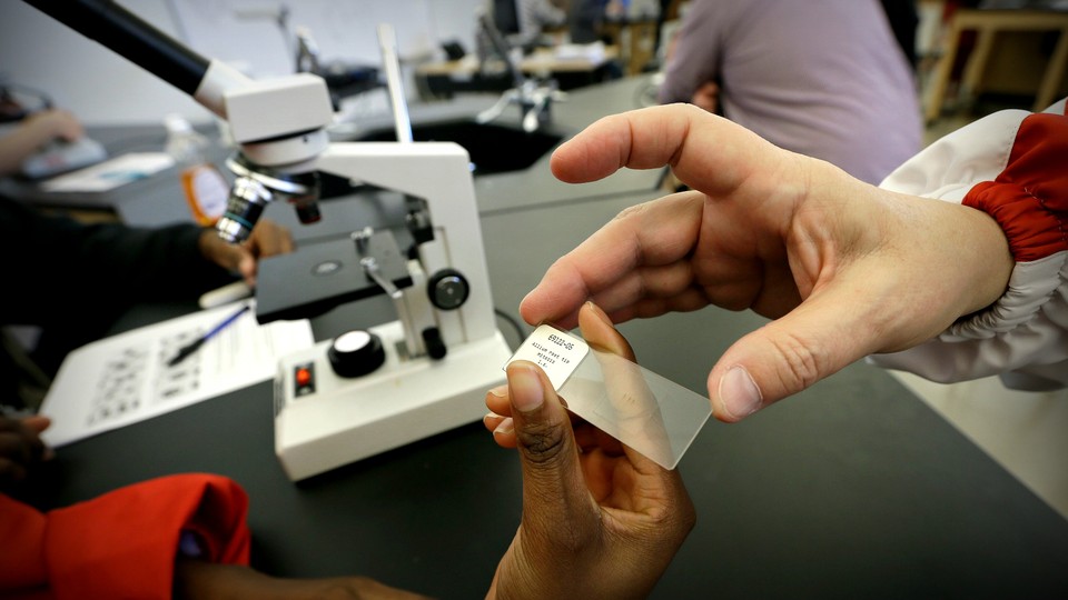 An African American student and a white student exchange a microscope slide in biology class in the North Little Rock school district in Arkansas, which was still under a court desegregation order as of 2014.