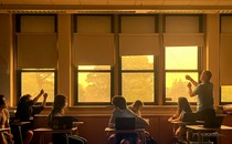 A teacher closes the shades of windows looking out on a haze of wildfire smoke.