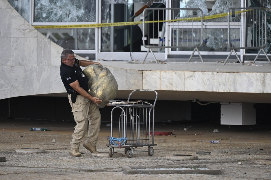 A worker carries the head of a statue outside a government building.