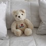 A teddy bear on a bed surrounded by pillows
