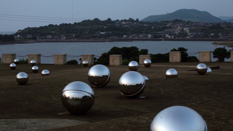 A memorial made of large metallic silver balls overlooking a bay and seaside town