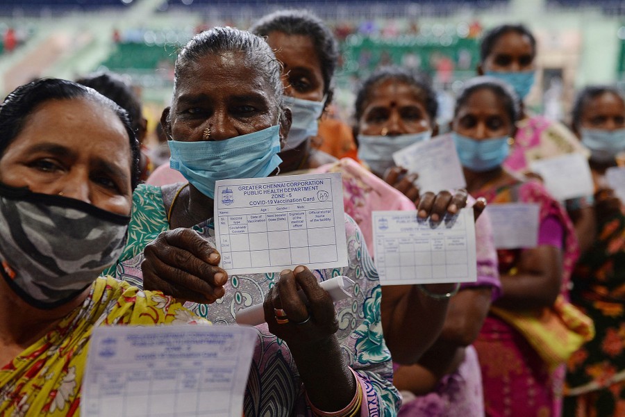 People hold up vaccination cards as they wait in line.