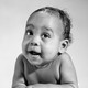 Black-and-white photos of two babies lying on their stomachs, smiling and looking off-frame