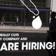 A man walks by a window with a hiring ad printed on it.