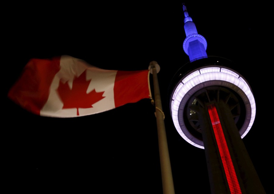 The CN Tower in blue, white, and red, next to a Canadian flag