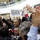 The Zaman editor in chief, Ekrem Dumanli, stands in a crowd of supporters and newspaper employees holding signs that say, in English and Turkish, "Free media cannot be silenced."